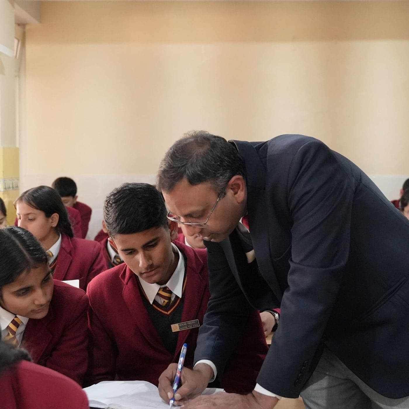 A teacher working through a problem with students at their desk